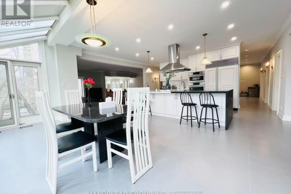 A sunroom with a dining table and chairs adjacent to a white kitchen and island. - 270 Greenbrooke Drive, Vaughan