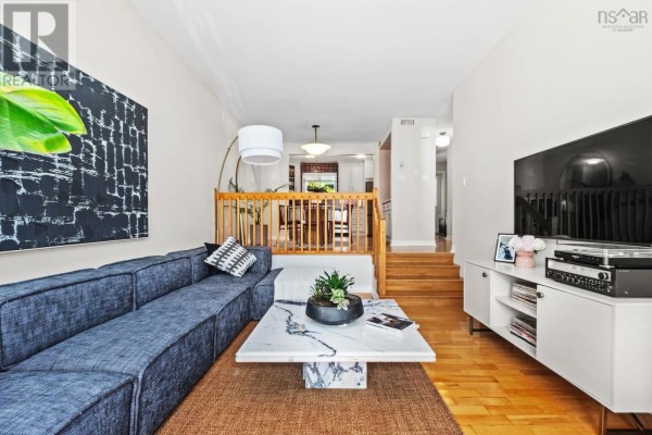 Living room with sofa, marble coffee table, and stairs leading to dining area. - 270 Spinnaker Drive, Armdale