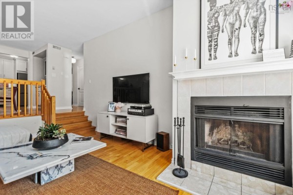 Living room with fireplace, television, and white media console. - 270 Spinnaker Drive, Armdale