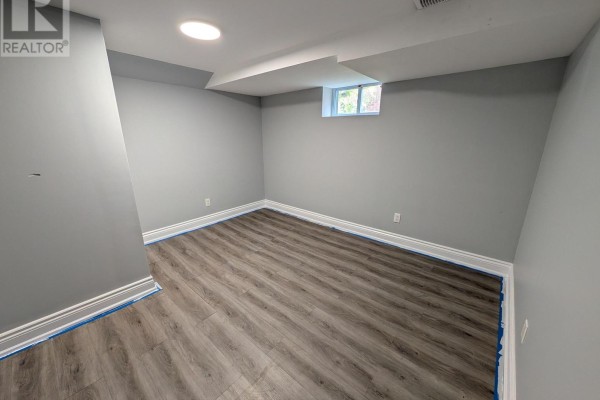 Empty basement bedroom with grey walls, baseboards, and a small window with a view of trees. - 270 Wilson Road S, Oshawa