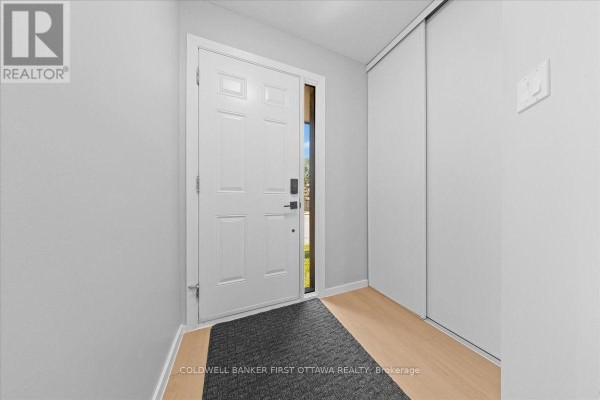 Interior view of the foyer with a white front door, grey walls, and wood-look flooring. - 2701 Pimlico Crescent, Ottawa