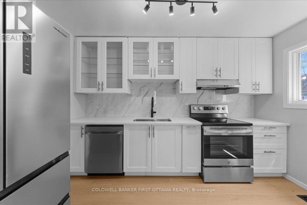 Modern white kitchen with stainless steel appliances, marble backsplash, and light wood flooring. - 2701 Pimlico Crescent, Ottawa