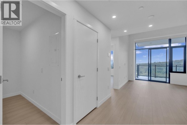 Hallway with white doors and white walls leading to the living area. - 2703 626 Claremont Street, Coquitlam