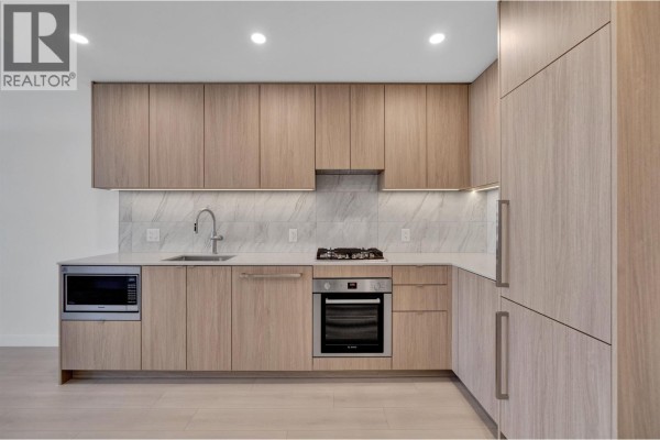 Modern kitchen with light wood cabinets, stainless steel appliances, and marble backsplash. - 2703 626 Claremont Street, Coquitlam