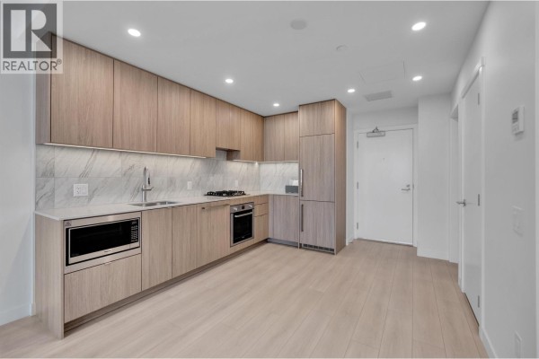 Corner kitchen view showing light wood cabinets, appliances, and light wood floors. - 2703 626 Claremont Street, Coquitlam