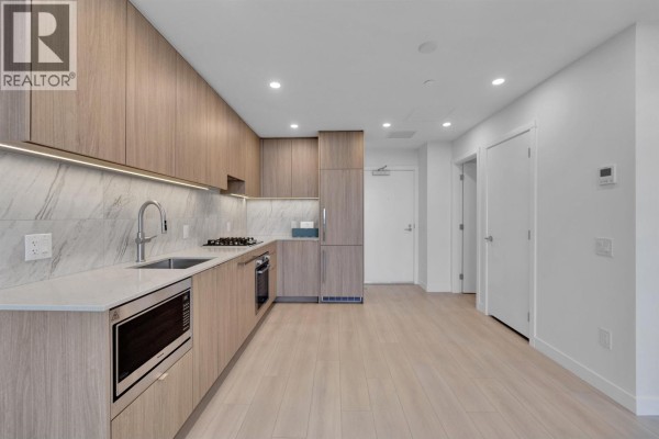 Kitchen with light wood cabinets, stainless steel appliances, and view towards the entrance. - 2703 626 Claremont Street, Coquitlam