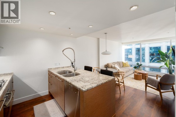 Kitchen island with granite countertop and sink, overlooking a living area with a sofa. - 2704 1111 Alberni Street, Vancouver