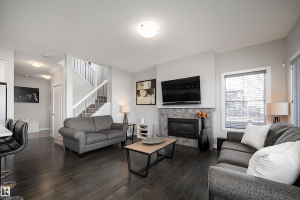 Interior hallway with white doors, grey tile flooring, and a white storage bench near a wall-mounted shelf. - 2704 Koshal Pl Sw, Edmonton