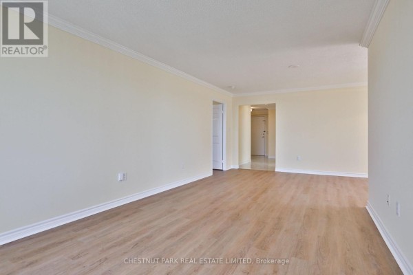 Empty living room with light wood floors, pale yellow walls, and doorway to hallway. - 2705 - 228 Bonis Avenue E, Toronto