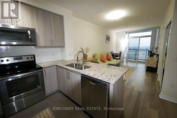 Apartment kitchen with stainless steel appliances, granite counters, and light wood cabinets. - 2706 - 3975 Grand Park Drive, Mississauga