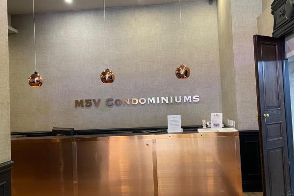 Building lobby with a copper reception desk and copper pendant lights. - 2708 - 375 King Street W, Toronto