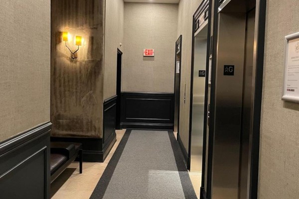 Elevator lobby with stainless steel elevators, textured walls, and a sconce light. - 2708 - 375 King Street W, Toronto