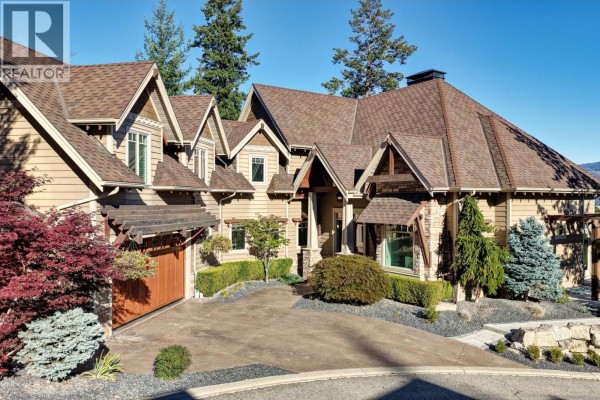 Front view of a large house with a circular driveway, tan siding, stone accents, and a wooden garage door. - 271 Chicopee Road Unit# 3, Vernon