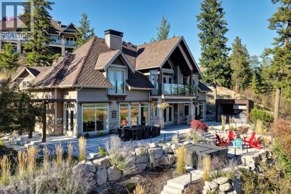 Rear view of a large house with a patio, hot tub, and seating area overlooking a landscaped yard. - 271 Chicopee Road Unit# 3, Vernon