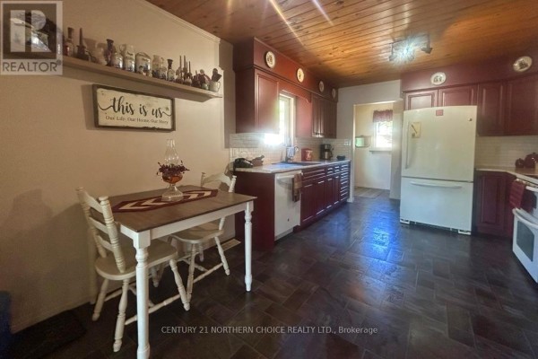 Living room with wood-paneled walls, large entertainment center, and carpeted floor. - 271 Japada Trail, Fort Frances