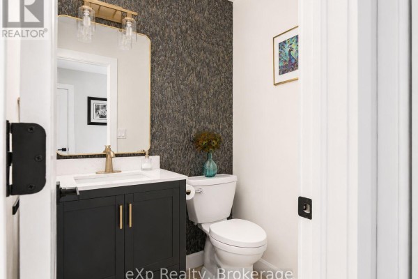 Modern bathroom with dark vanity, gold fixtures, textured wallpaper, and peacock art - 271 River Road Grey Highlands