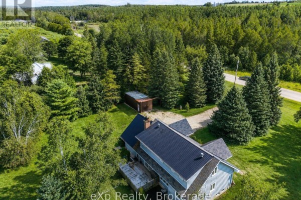 House with wood deck and outbuilding among trees - 271 River Road Grey Highlands