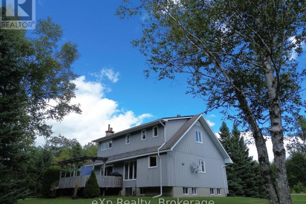 Grey two-story house with wood deck and chimney - 271 River Road Grey Highlands
