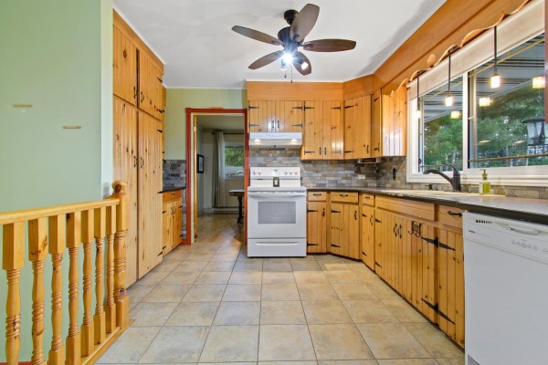 Kitchen with light wood cabinets, white appliances, stone tile backsplash, and tile flooring. - 271 Rue Leguerrier O., Mansfield Et Pontefract