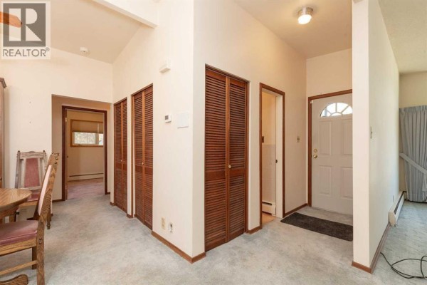 Hallway inside the home showing multiple louvered closets and doorways. - 2710 6a Avenue N, Lethbridge