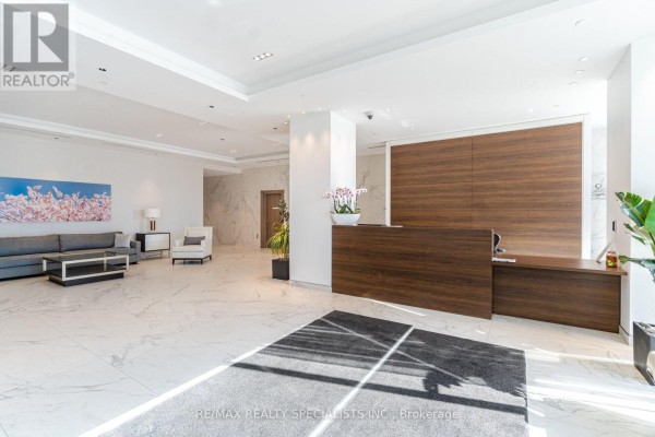 A modern lobby with a marble floor, a dark wood reception desk, and contemporary furniture. - 2711 - 1926 Lake Shore Boulevard, Toronto