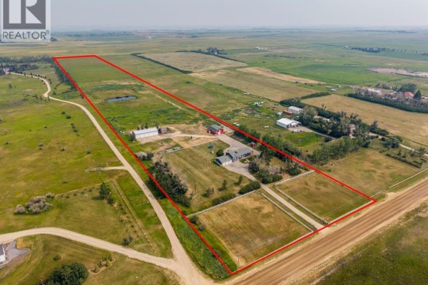 Expansive aerial view of the entire property, including the house, barns, fields, and surrounding rural landscape, outlined in red. - 271154 Range Road 285, Rural Rocky View County