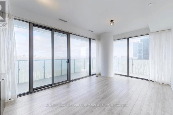 Empty living room with light wood floors, floor-to-ceiling windows, and balcony access. - 2712 - 50 Charles Street E, Toronto