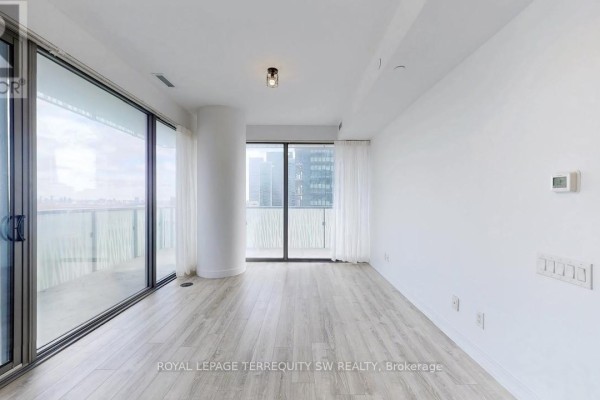 Bright, empty living room with light wood floors and large windows with sheer curtains. - 2712 - 50 Charles Street E, Toronto