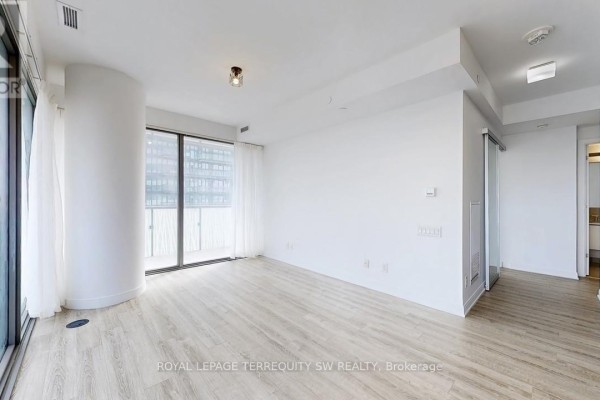 Empty living room with light wood floors, floor-to-ceiling windows, and an entrance doorway. - 2712 - 50 Charles Street E, Toronto