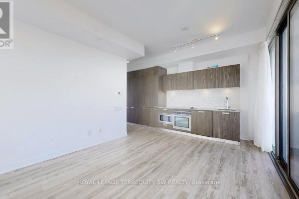 Open concept living area with light wood floors and a modern kitchen with wood cabinets. - 2712 - 50 Charles Street E, Toronto