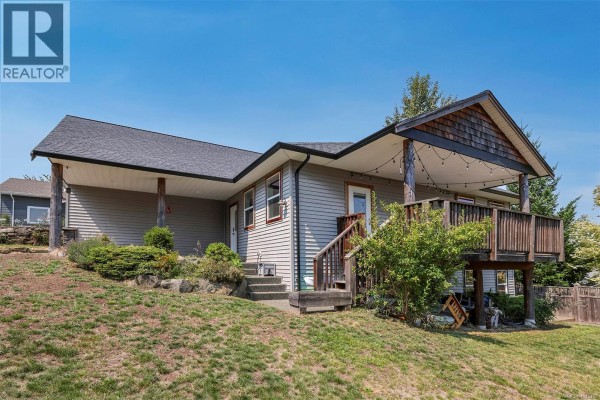 View of the house from the side yard, showing the covered deck and grey siding. - 2712 Rydal Ave, Cumberland