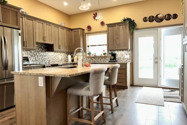 Kitchen island with granite countertop and two upholstered stools, adjacent to stainless steel appliances. - 27123 Park 70n Road, Springfield Rm