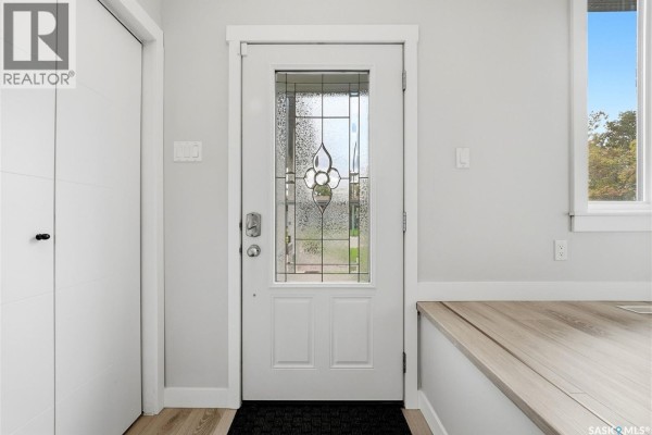 Interior view of a home's entrance with a white door with decorative glass and light grey walls. - 2714 Jaques Place E, Regina
