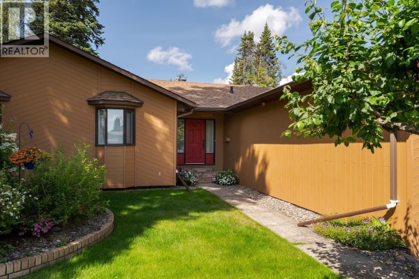 Close-up of the house entrance with a red door and surrounding plants. - 2715 Wildwood Crescent, Prince George