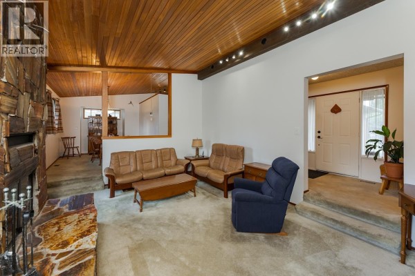 View of the living room with a fireplace, sofas, and an entryway. - 2715 Wildwood Crescent, Prince George