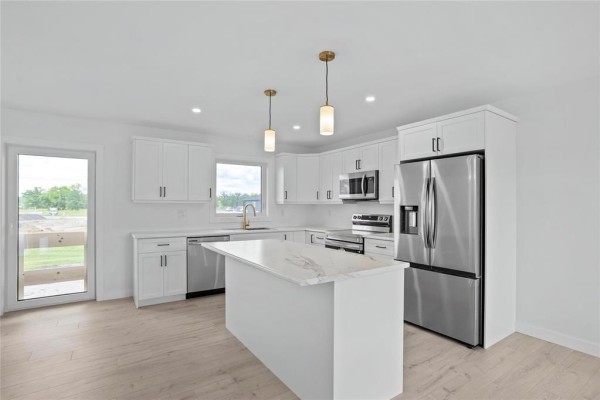 White kitchen with stainless steel appliances, island, and marble countertops. - 272 Fernwood Way, New Bothwell