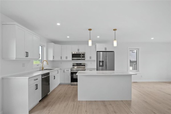 Bright white kitchen with shaker cabinets, island, and stainless steel appliances. - 272 Fernwood Way, New Bothwell