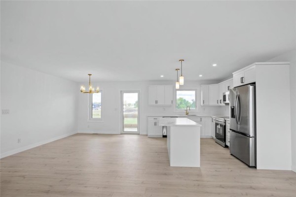 Open concept living and kitchen area with white walls and light wood floors. - 272 Fernwood Way, New Bothwell