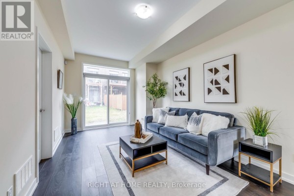 Living room with dark hardwood floors, a blue sofa, and a sliding glass door to the backyard. - 272 Squire Crescent, Oakville