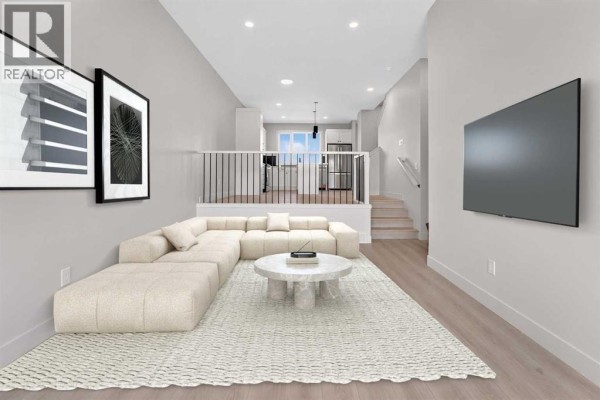 Living room with a television, stairs, and view of the kitchen area. - 2720 16 Avenue, Coaldale