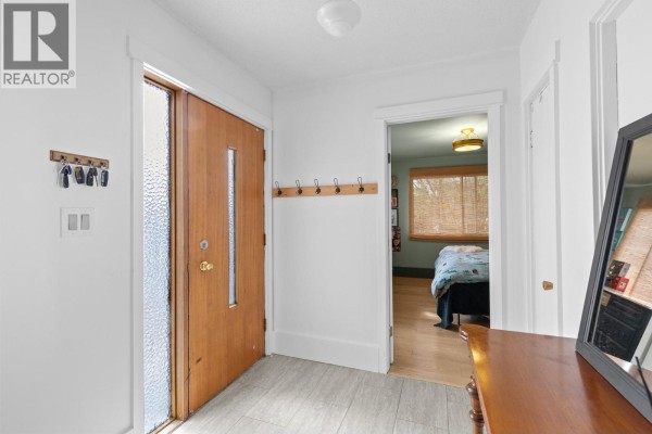 Interior entryway with hardwood double front doors, tiled floor, and hallway to bedroom. - 2720 Casa Loma Road, West Kelowna