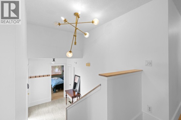 Interior view of staircase landing with modern chandelier and hallway to bedroom. - 2720 Casa Loma Road, West Kelowna