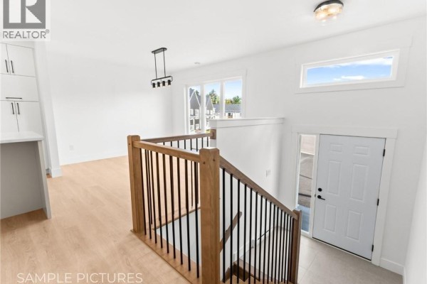 Interior entryway with light wood floors, white walls, and dark metal staircase. - 273 Elsliger Street, Dieppe