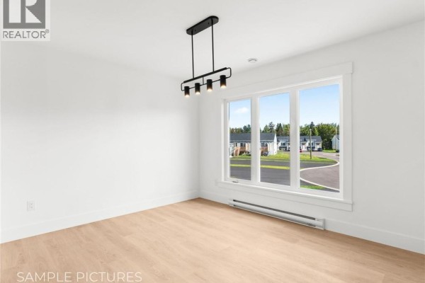 Empty room with light wood floors, white walls, and a large window. - 273 Elsliger Street, Dieppe