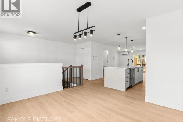 Open concept living area with light wood floors, white walls, and a kitchen island. - 273 Elsliger Street, Dieppe