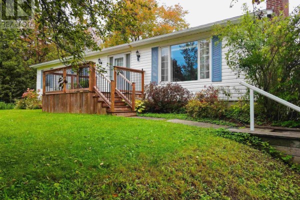 Side view of the white house with a wooden deck, white siding, and blue shutters. - 273 Highway 1, Mount Uniacke