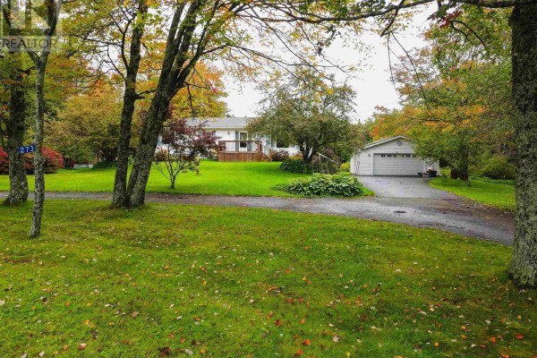 View of the white house and detached garage from across the street, with trees and fall foliage. - 273 Highway 1, Mount Uniacke