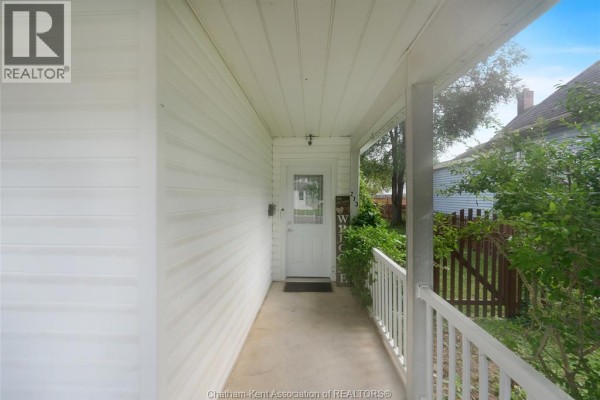 Side view of the covered porch leading to a white front door with a window. - 273 St Clair Street, Chatham