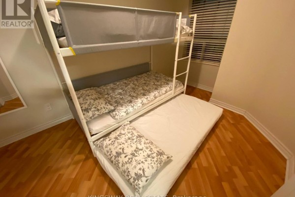 Bunk beds with white metal frame and patterned bedding in a room with wood floors. - 2730 - 3888 Duke Of York Boulevard, Mississauga