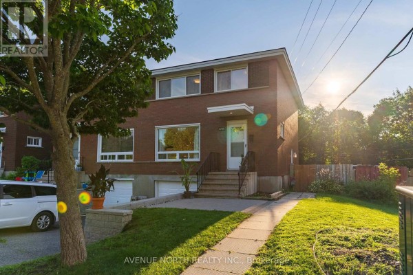 Red brick multi-family home with two garage doors and a sidewalk leading to the front entrance. - 2732-2730 Colman Street, Ottawa